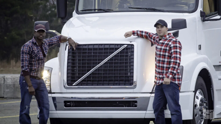 A picture of a parked truck with two drivers in front of it